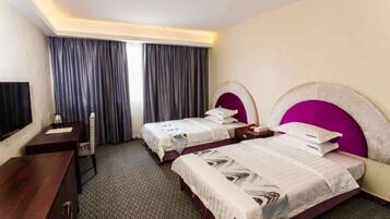 Une chambre d’hôtel avec deux lits, un bureau et une télévision.