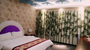 Habitación de hotel con una cama, una pared con plantas de bambú verticales y un techo con paraguas azules.