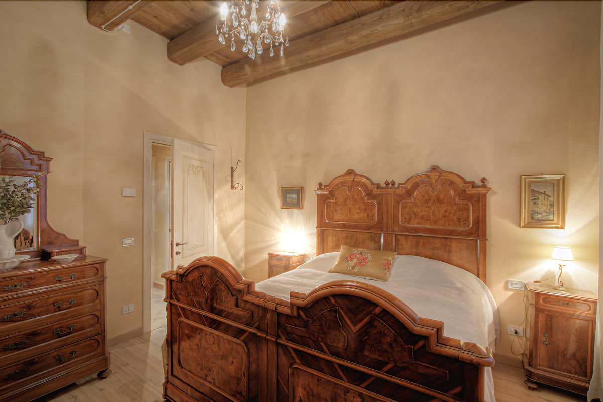 Une chambre à coucher avec un lit en bois, une commode, une table de chevet et un lustre.