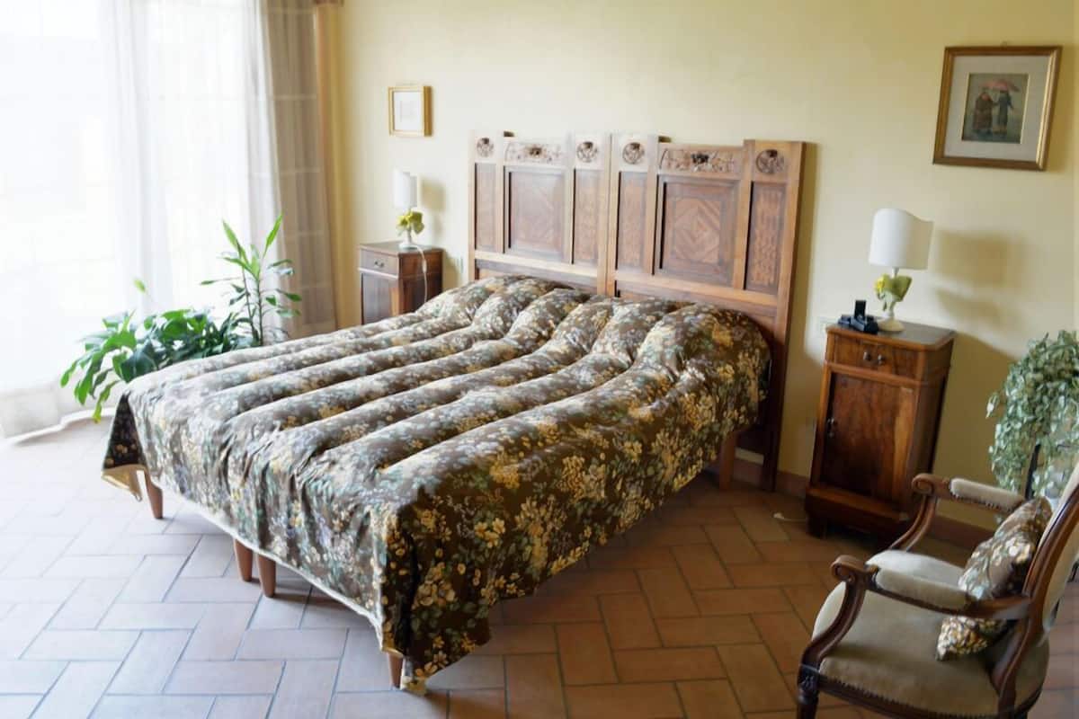 Une chambre à coucher avec un grand lit, une table de chevet en bois, une chaise et un placard.
