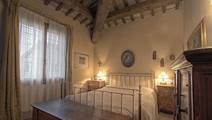 A bedroom with a wooden bed, a nightstand, a dresser, and a window with curtains. - La Fornasaccia (Cesena)