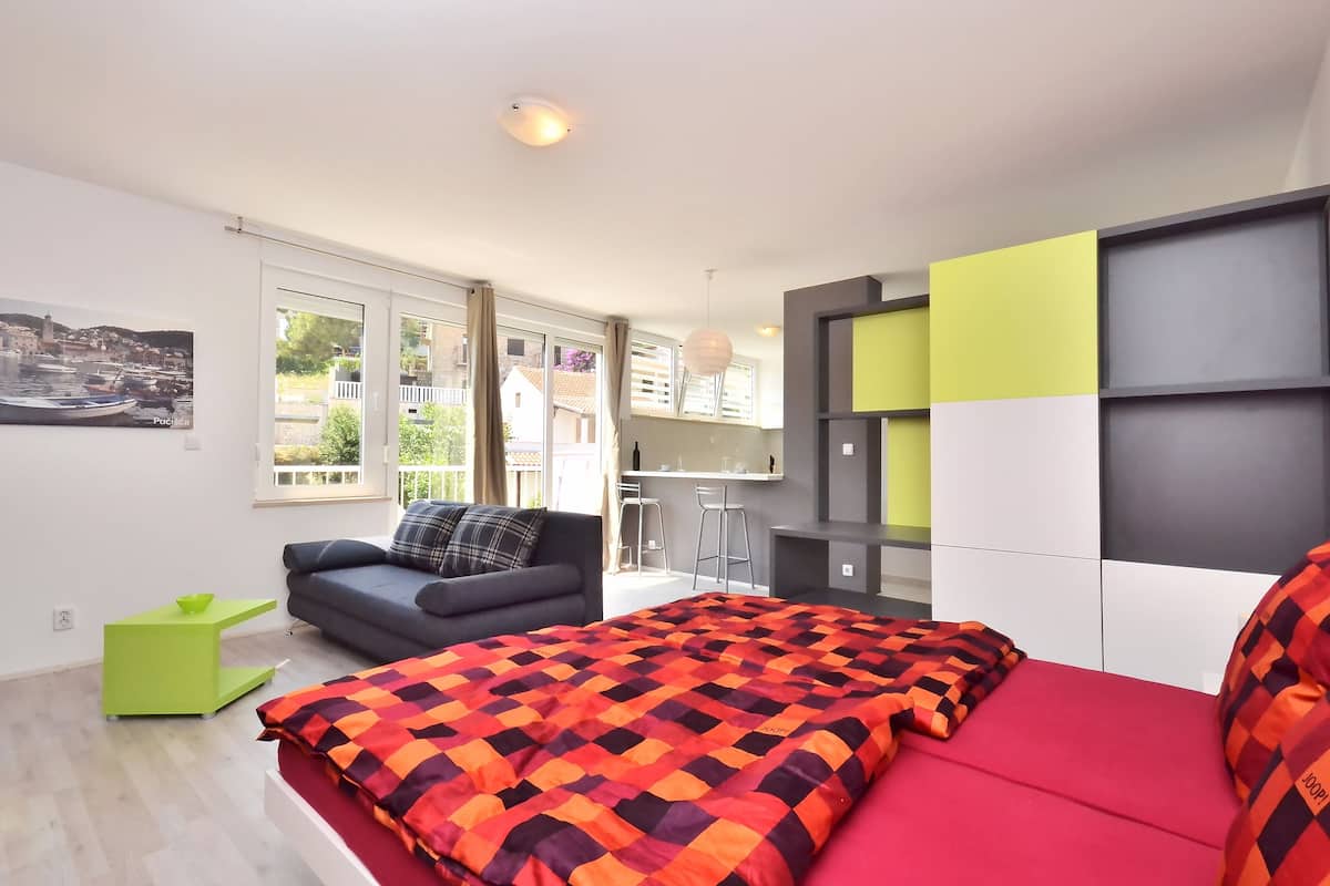 Un dormitorio moderno con cama, sofá, escritorio y vistas al exterior.