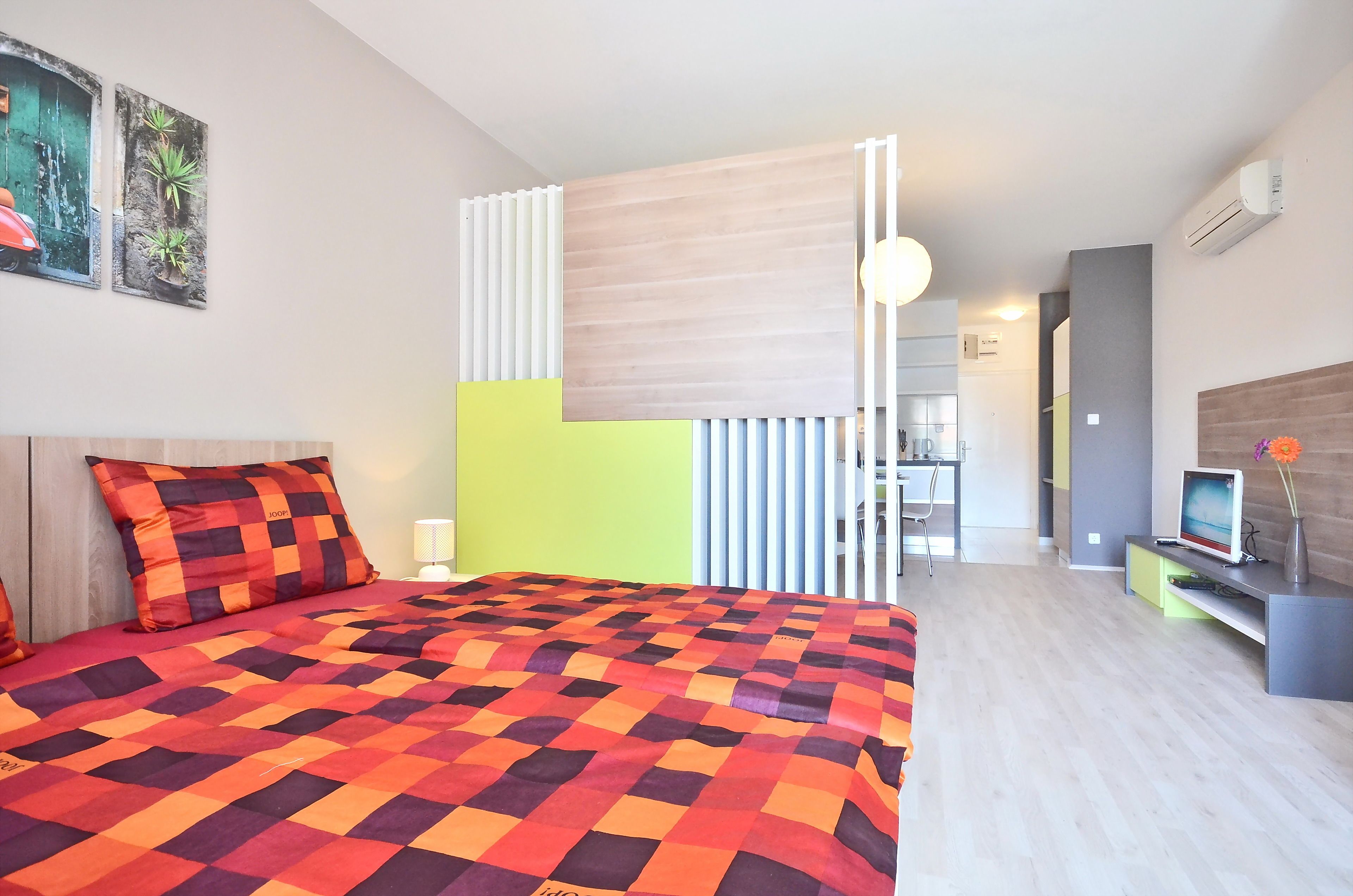 Ett modernt hotellrum med en stor säng, ett skrivbord med en dator och utsikt över köksdelen.