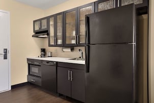 Una cocina moderna con armarios oscuros, un refrigerador de acero inoxidable y un horno empotrado.