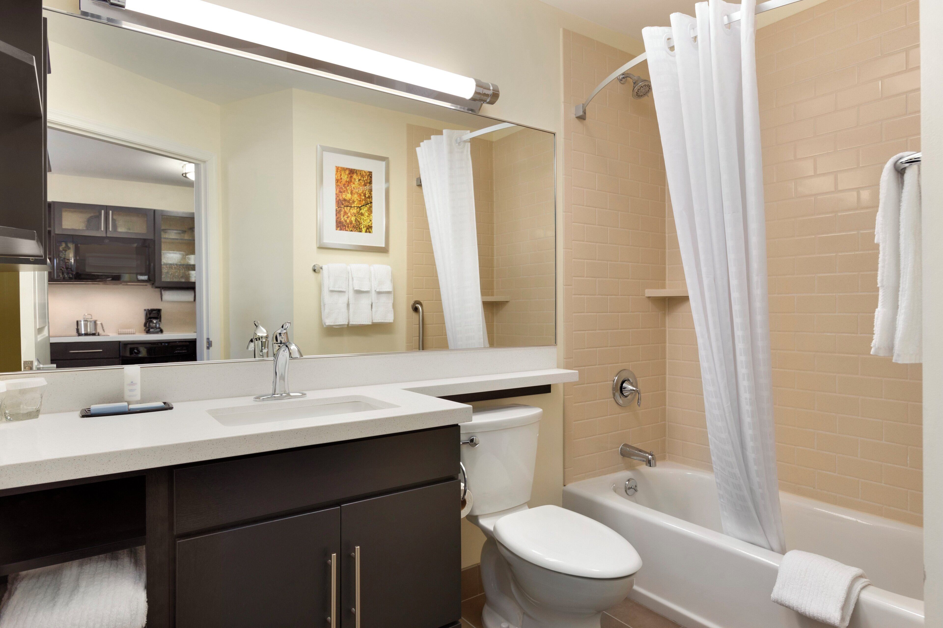 A modern bathroom with a white sink, a toilet, a bathtub, and a shower curtain.
