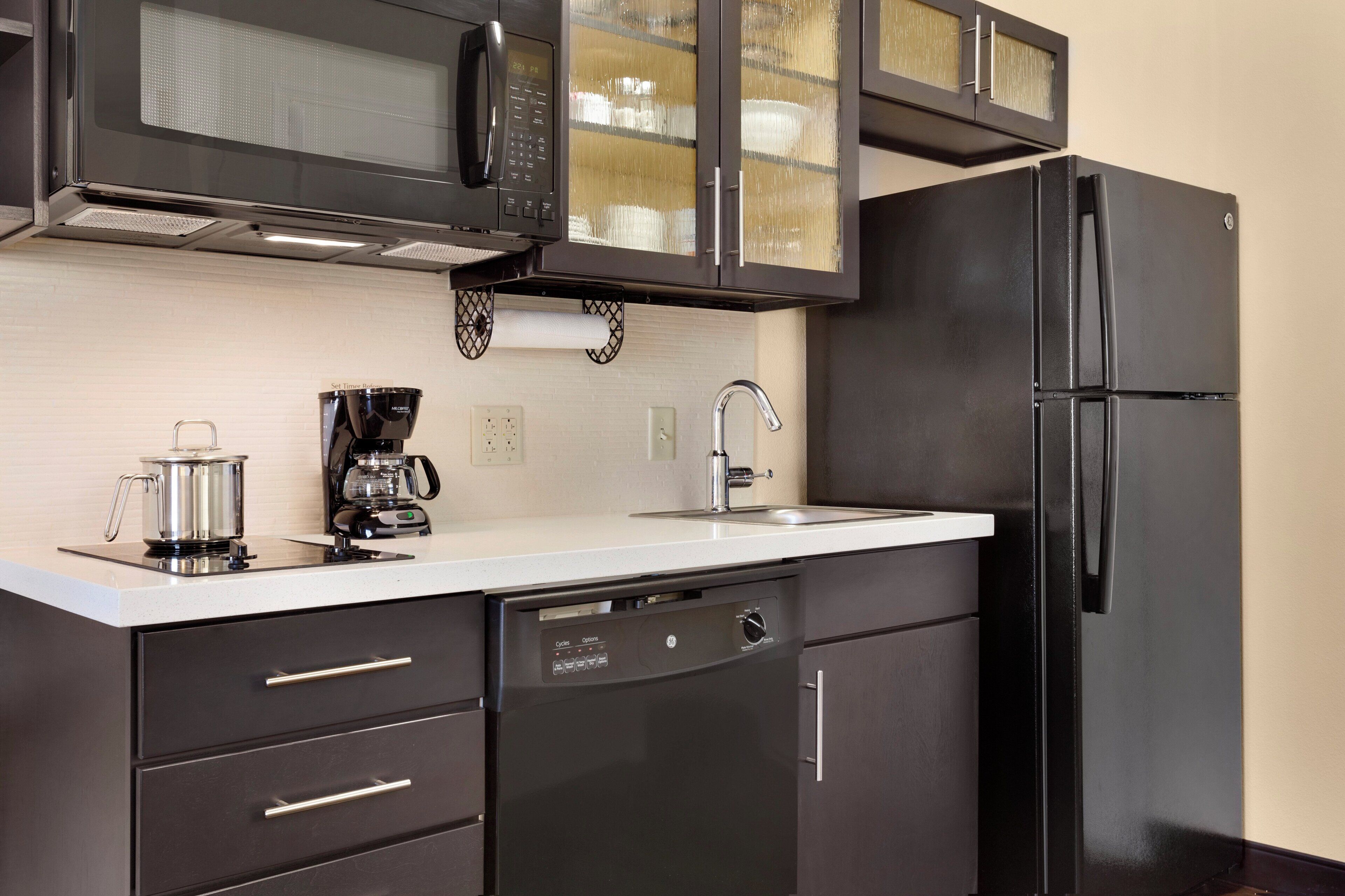 A modern kitchen with a black refrigerator, a coffee maker, and a microwave.