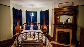 Een slaapkamer met een hemelbed, een open haard en een kroonluchter.