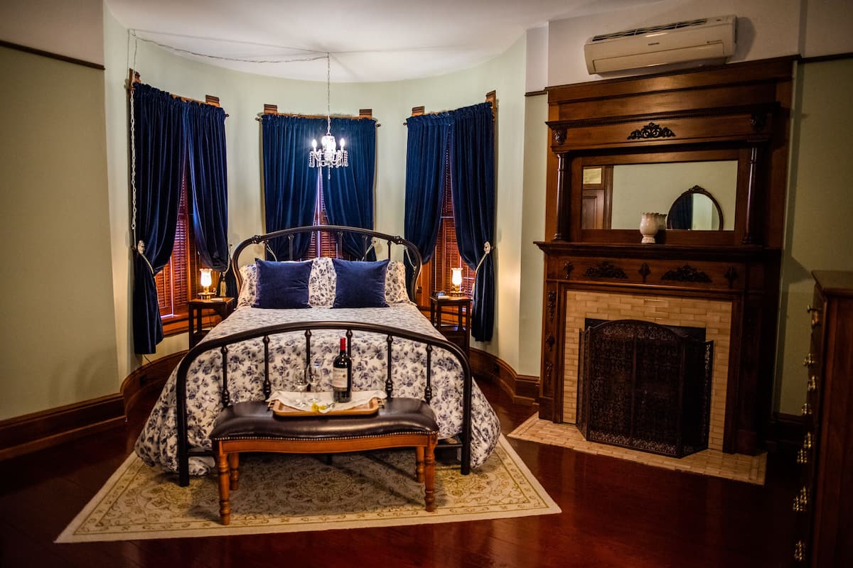 Une chambre à coucher avec un lit à baldaquin, une cheminée et un lustre.