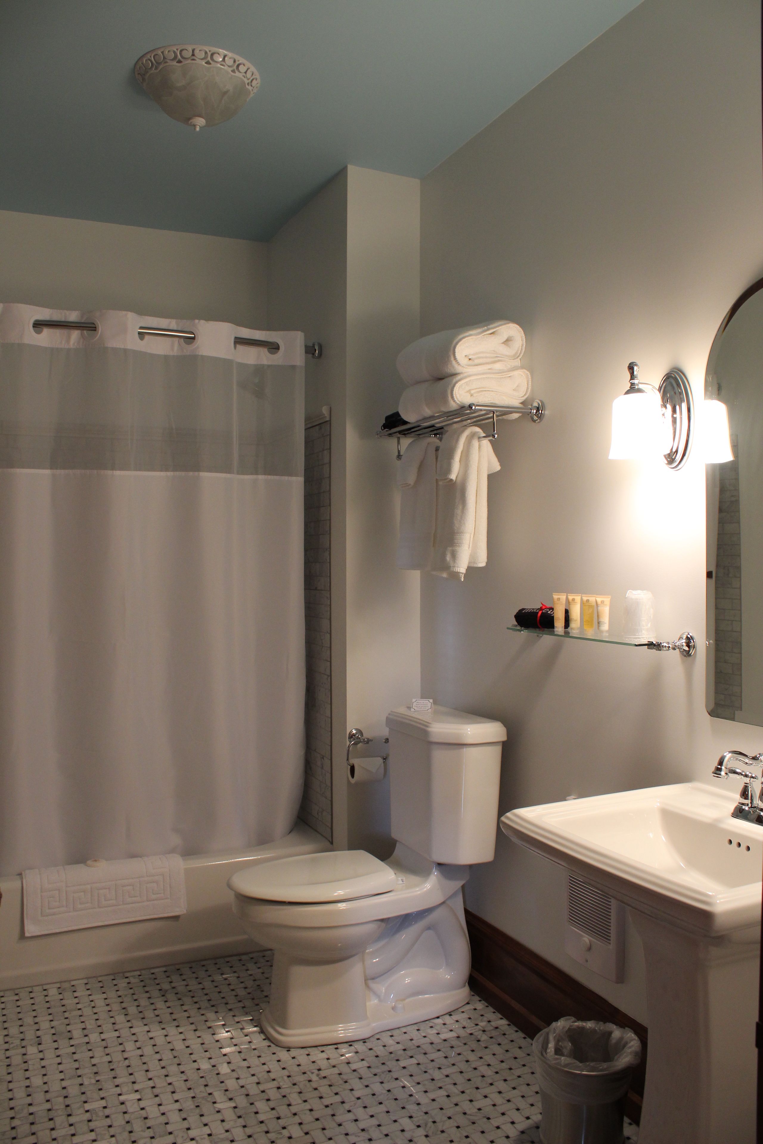 A bathroom with a toilet, sink, shower, and a towel rack.