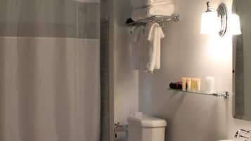 A bathroom with a toilet, sink, shower, and a towel rack.