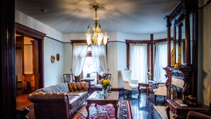 Een klassieke woonkamer met een bank, fauteuils, een salontafel en een kroonluchter.