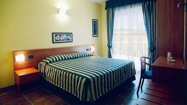 A hotel room with a bed, a nightstand, a desk, and a chair. - Hotel Blue Ribbon (Vercelli)