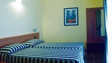 Quarto com duas camas, uma cabeceira de madeira, uma mesa de cabeceira, um quadro emoldurado na parede e uma porta com cortina.