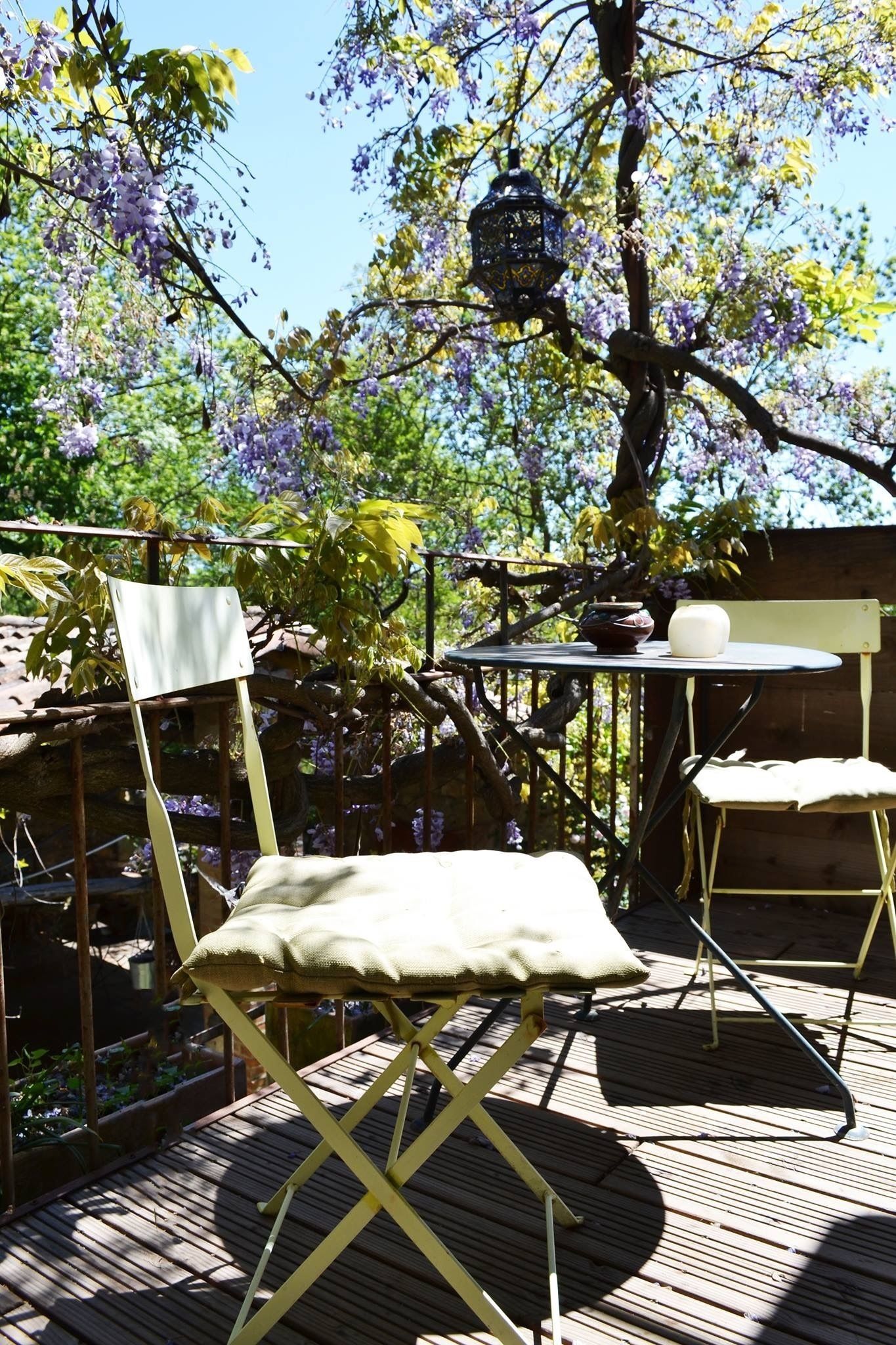 Un área de estar al aire libre con terraza de madera, una mesa de metal y una silla.