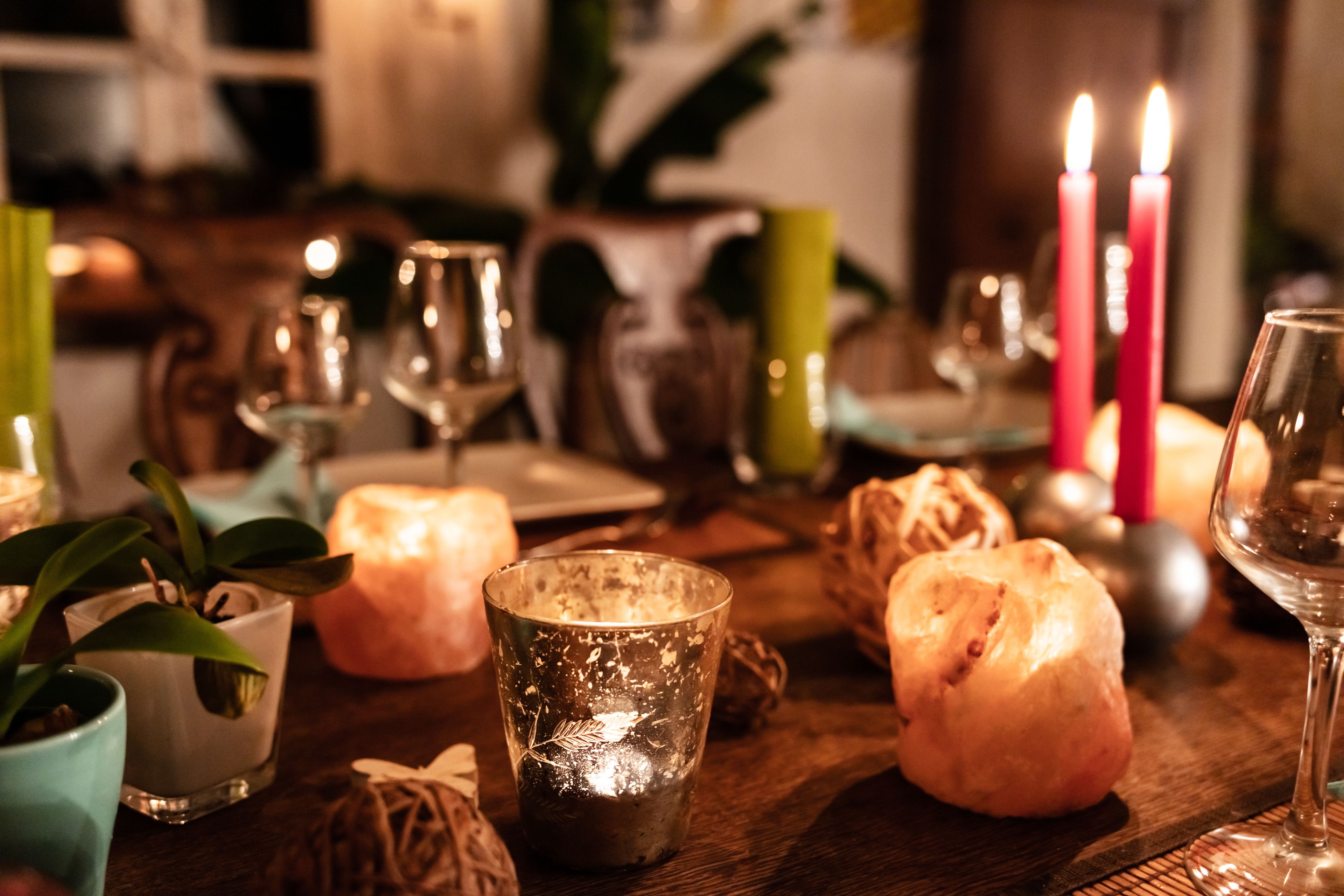 Uma mesa de jantar com velas, copos e uma planta.