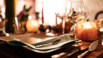 A dining table set with a green placemat, a spoon, a knife, and a glass of white wine.