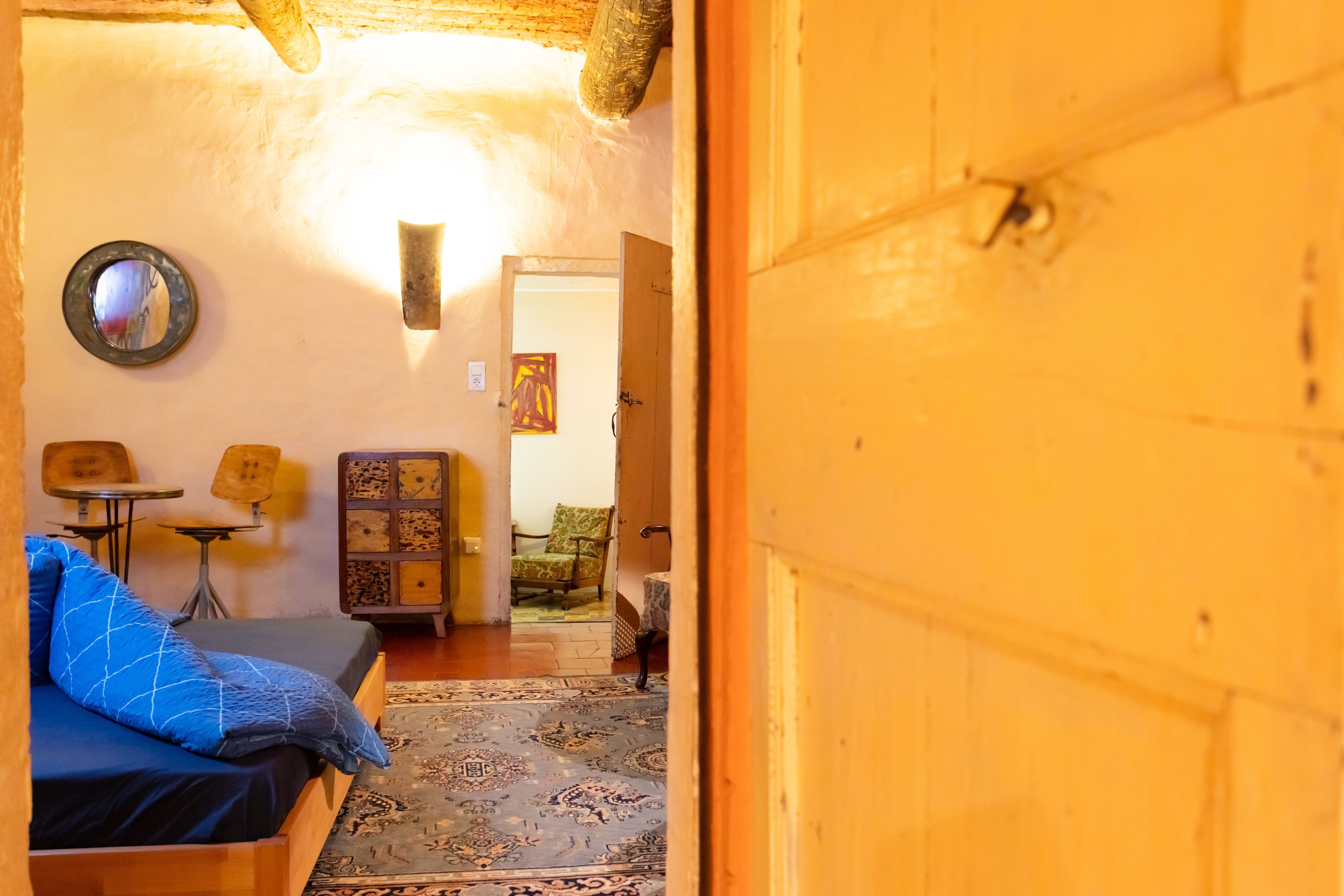 A cozy room with a bed, a small table, a chair, and a rug.