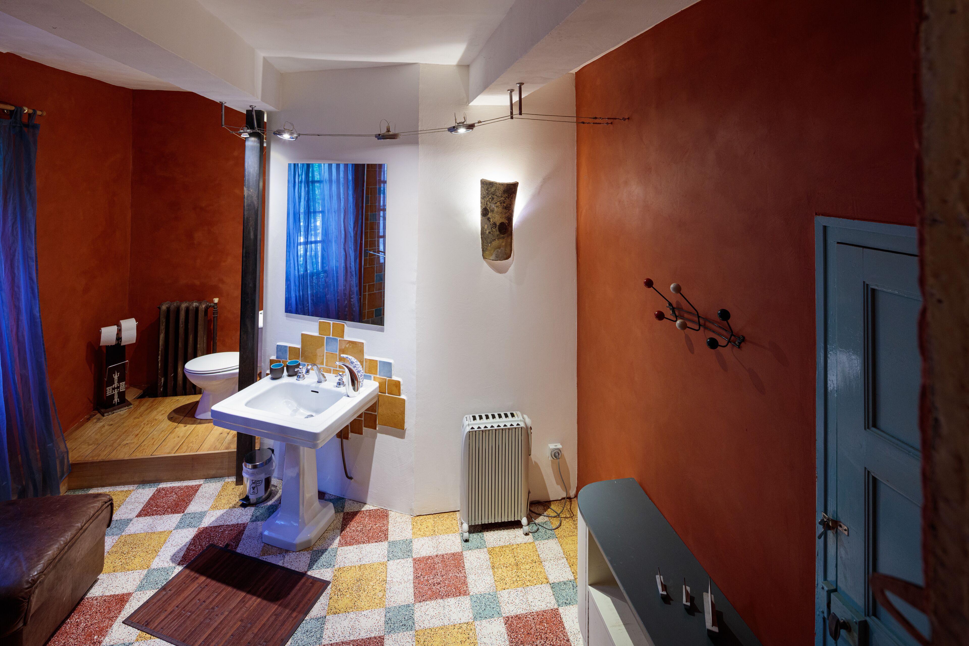 Een badkamer met een wit wastafelmeubel, toilet, radiator en een blauwe deur.