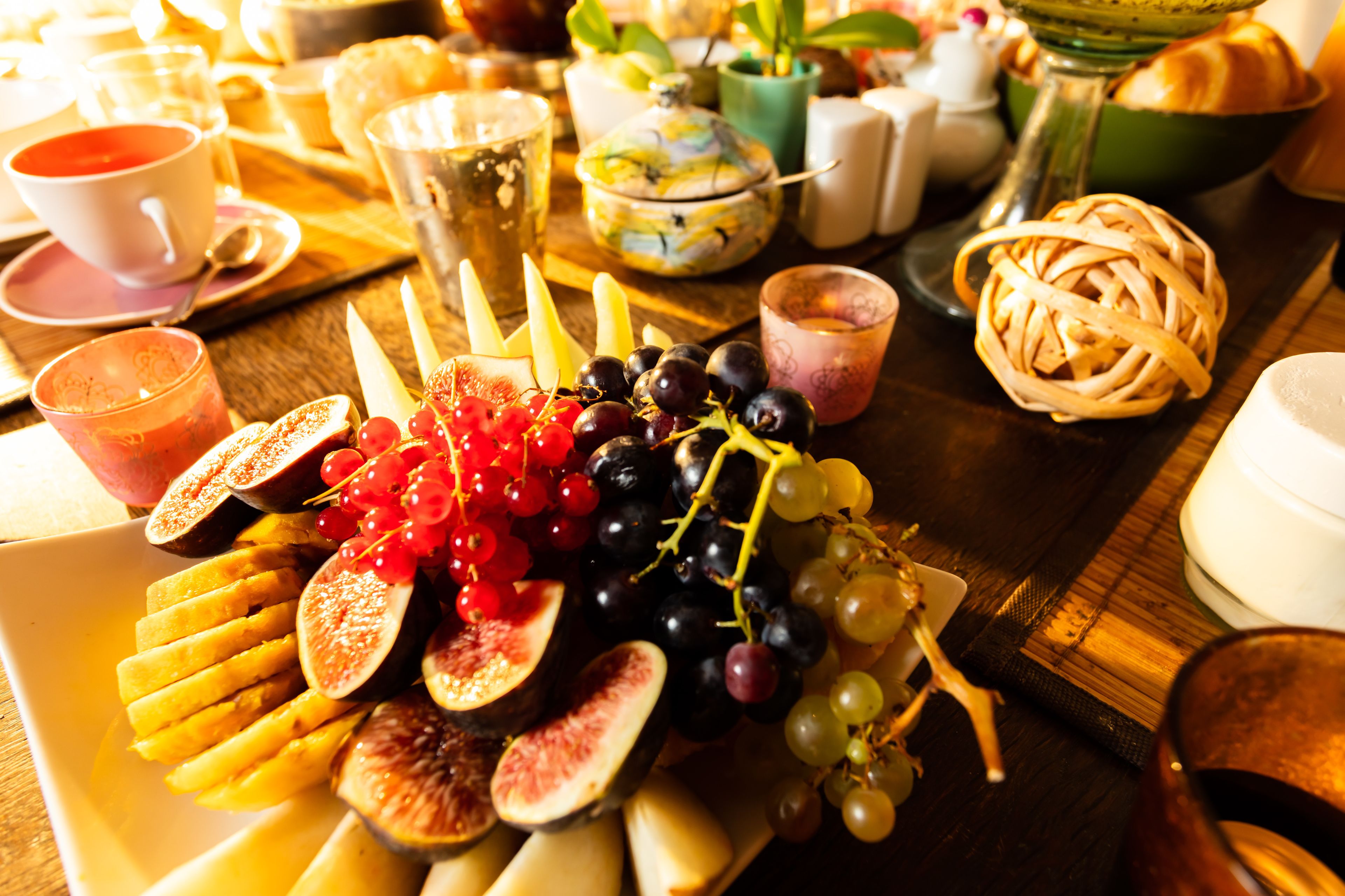 A breakfast setting with a variety of fruits, pastries, and beverages on a wooden table.