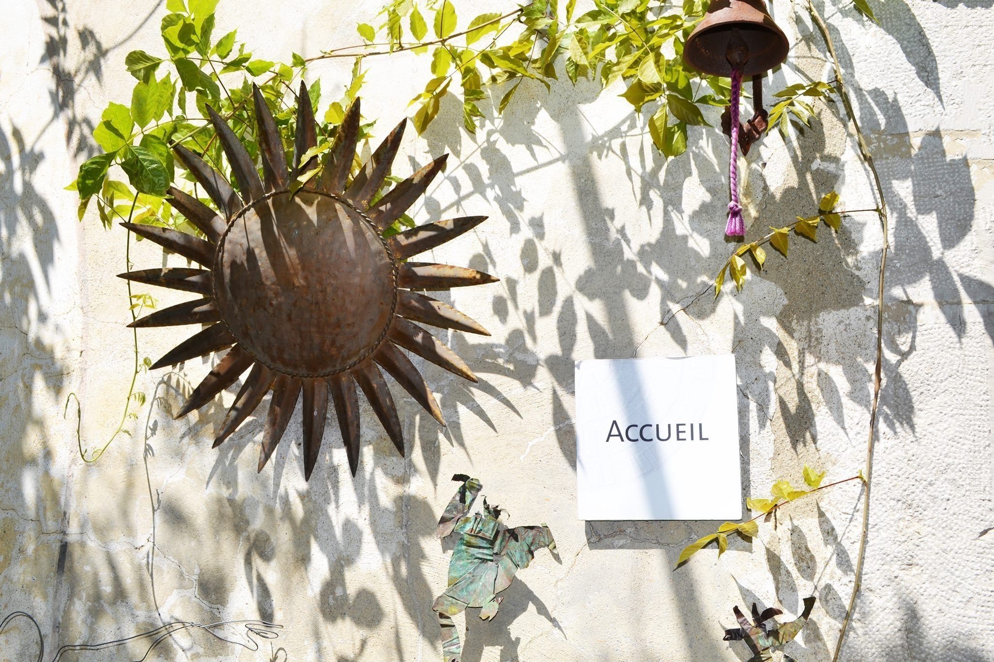 A wall-mounted sun decoration with a sign reading "Accueil" and a small statue.