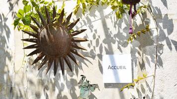 A wall-mounted sun decoration with a sign reading "Accueil" and a small statue.