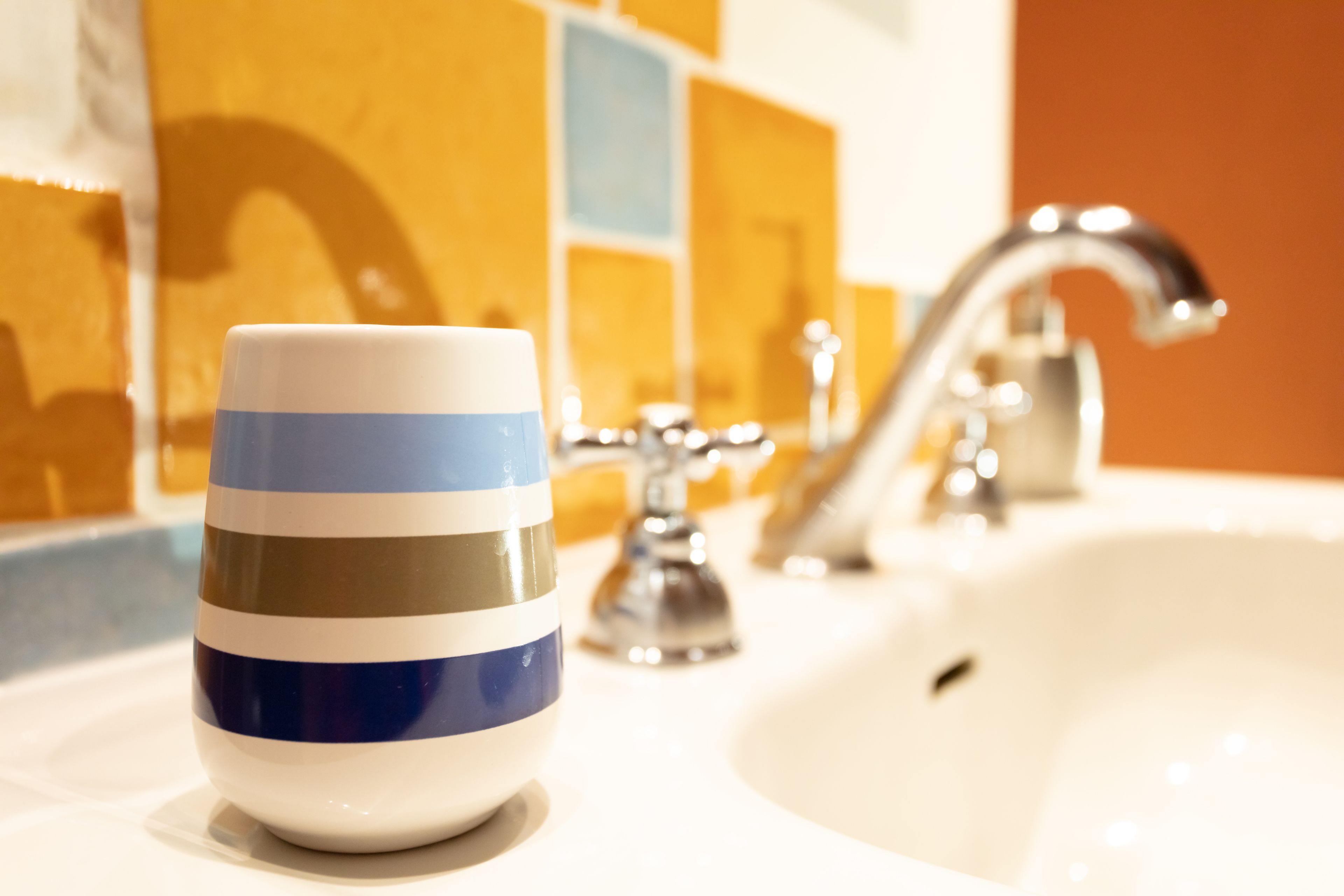 A bathroom with a sink, a cup, and a mirror.