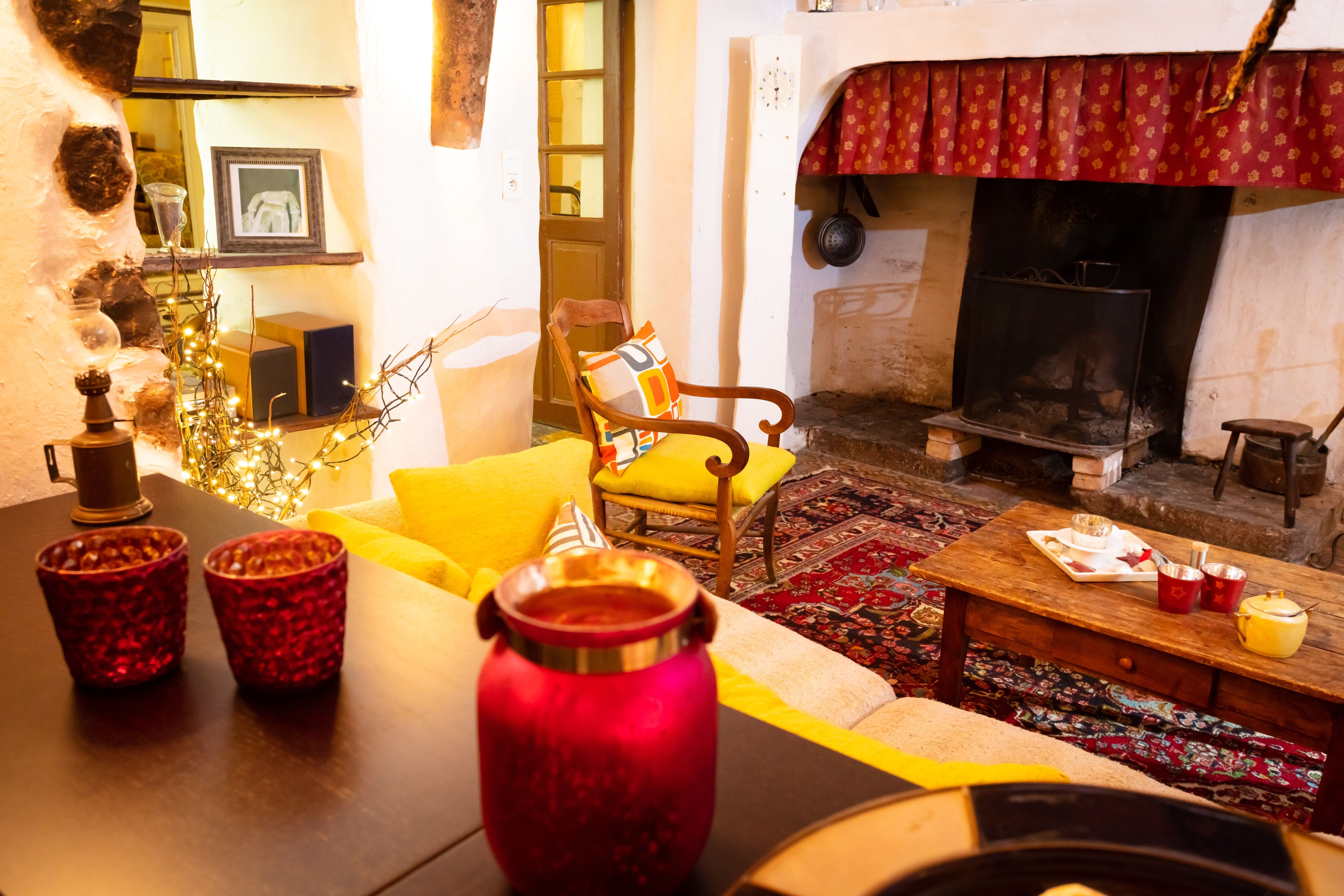 A cozy living room with a fireplace, a wooden table with a vase, and a yellow sofa.