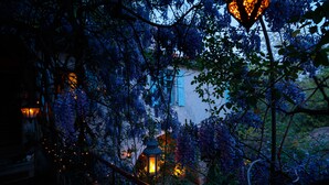 A garden with a white building, lanterns, and dense foliage.