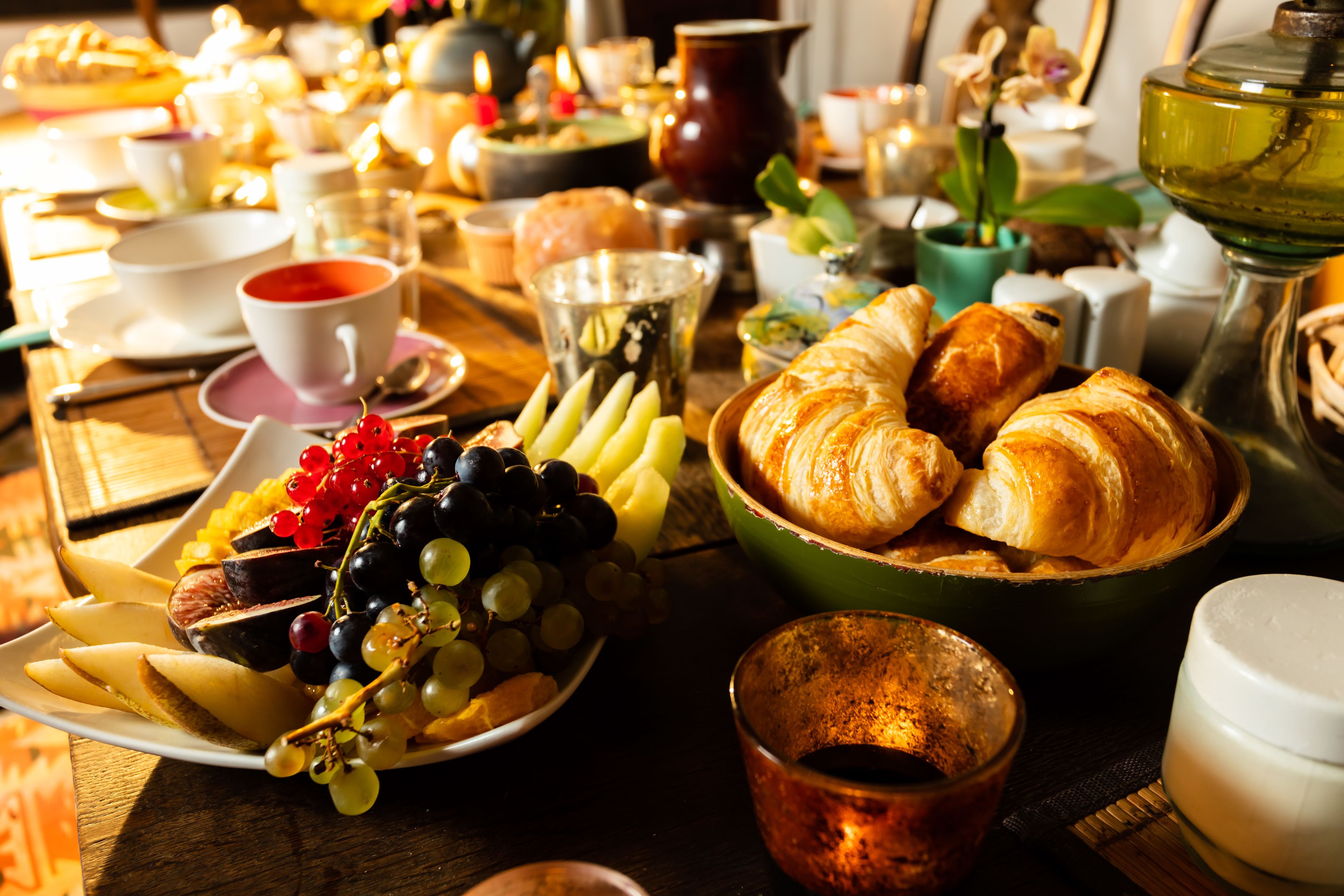 A table set with various food items including fruits, pastries, and beverages.