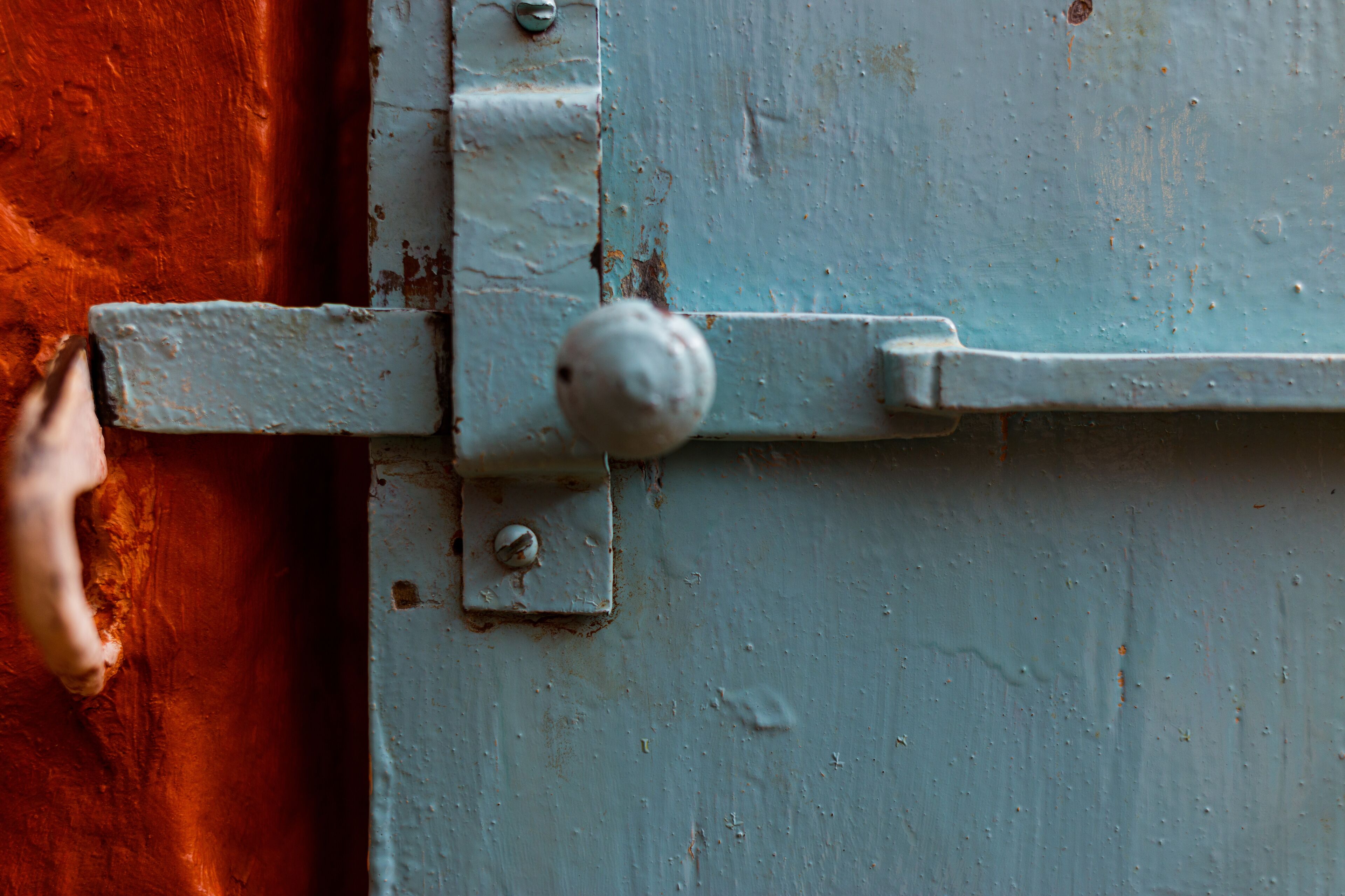A close-up of a metal latch on a door with a rusted orange surface.