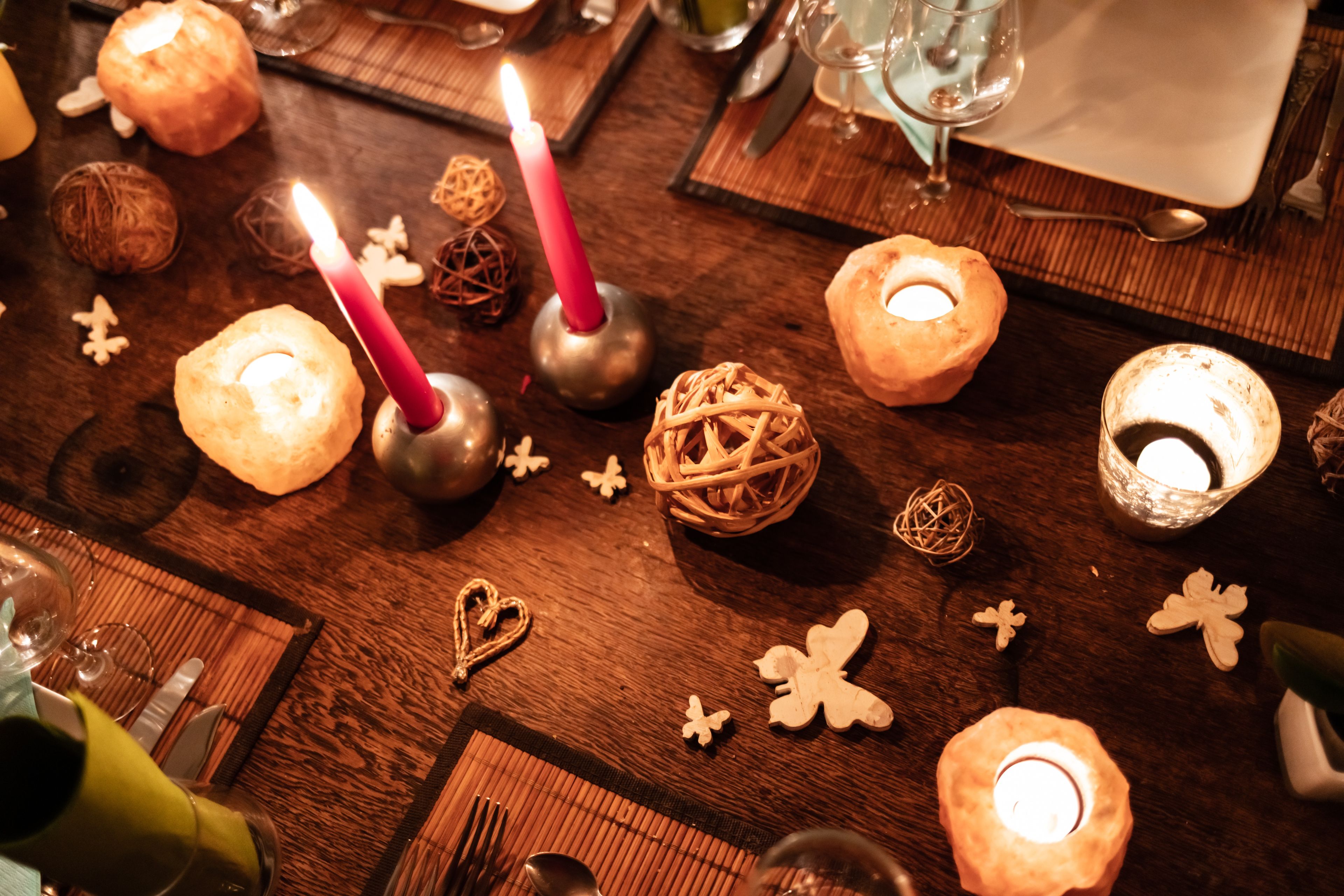 Une table mise pour un repas, avec des bougies, des objets décoratifs et un set de table.