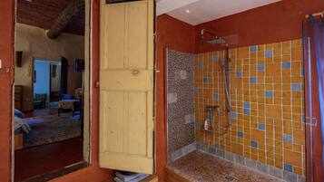 Un baño con ducha, paredes de azulejos y una puerta de madera.