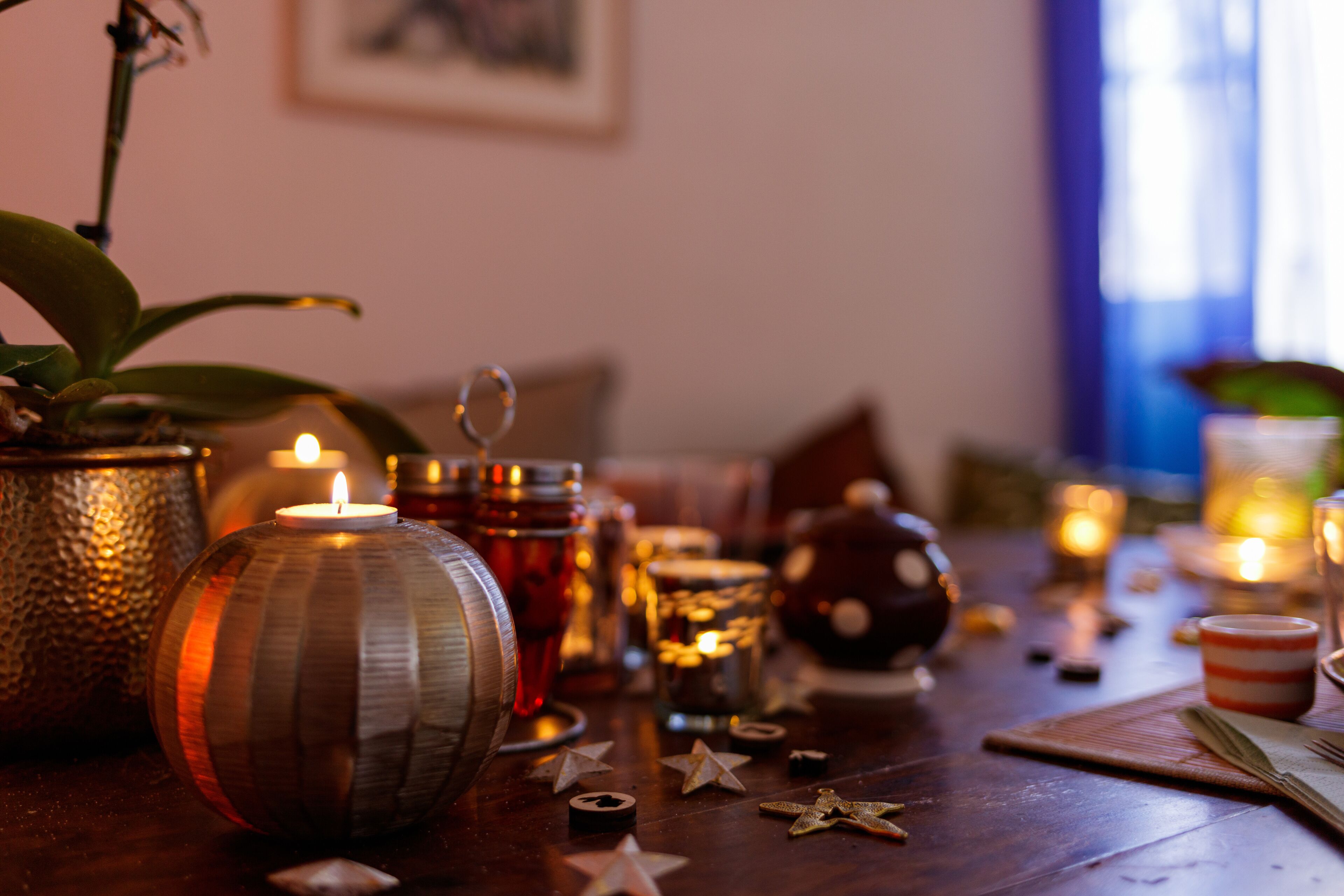 A table with candles, a lit candle, and star-shaped decorations.