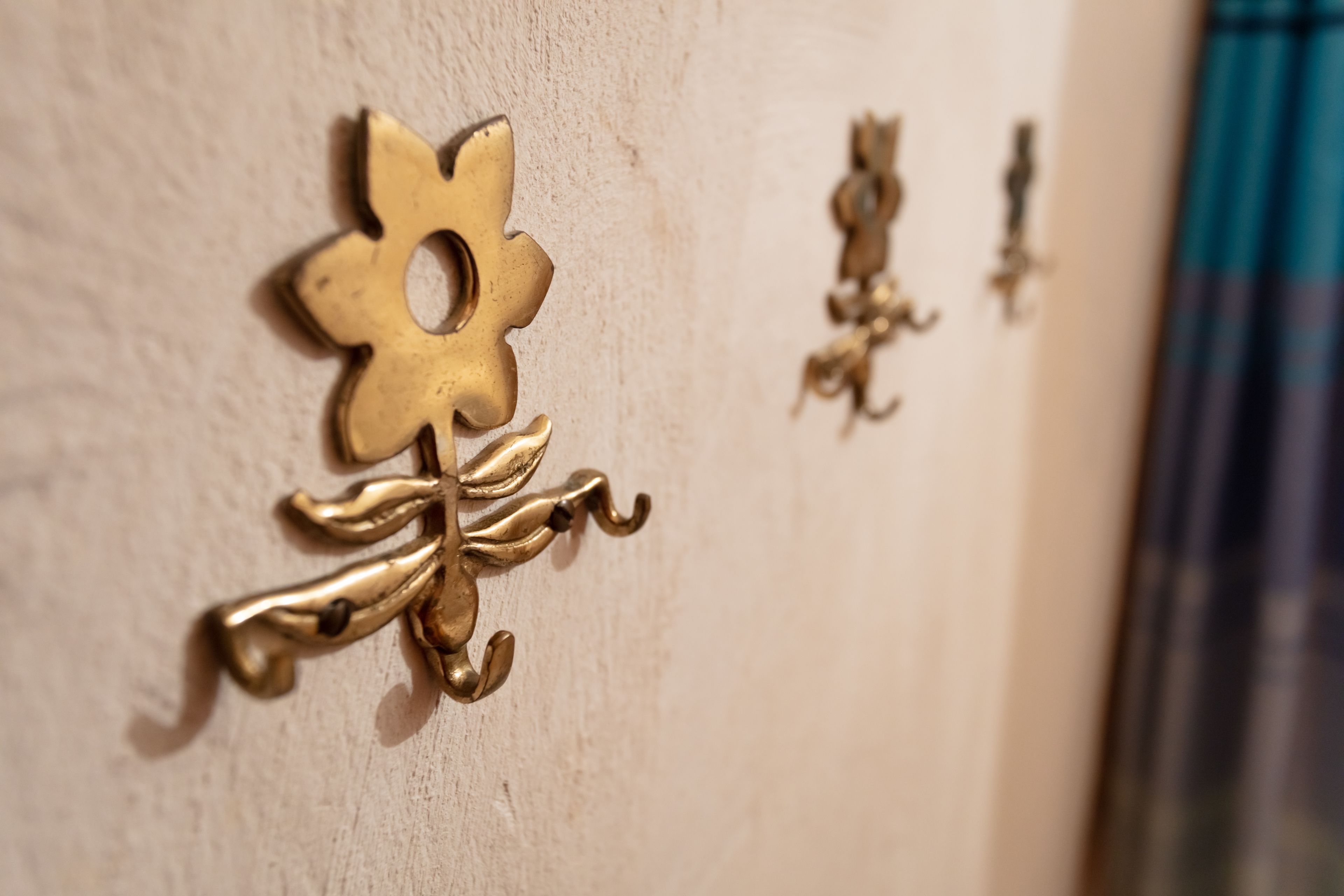 Gros plan sur des poignées en laiton, fixées au mur et ayant la forme de fleurs.