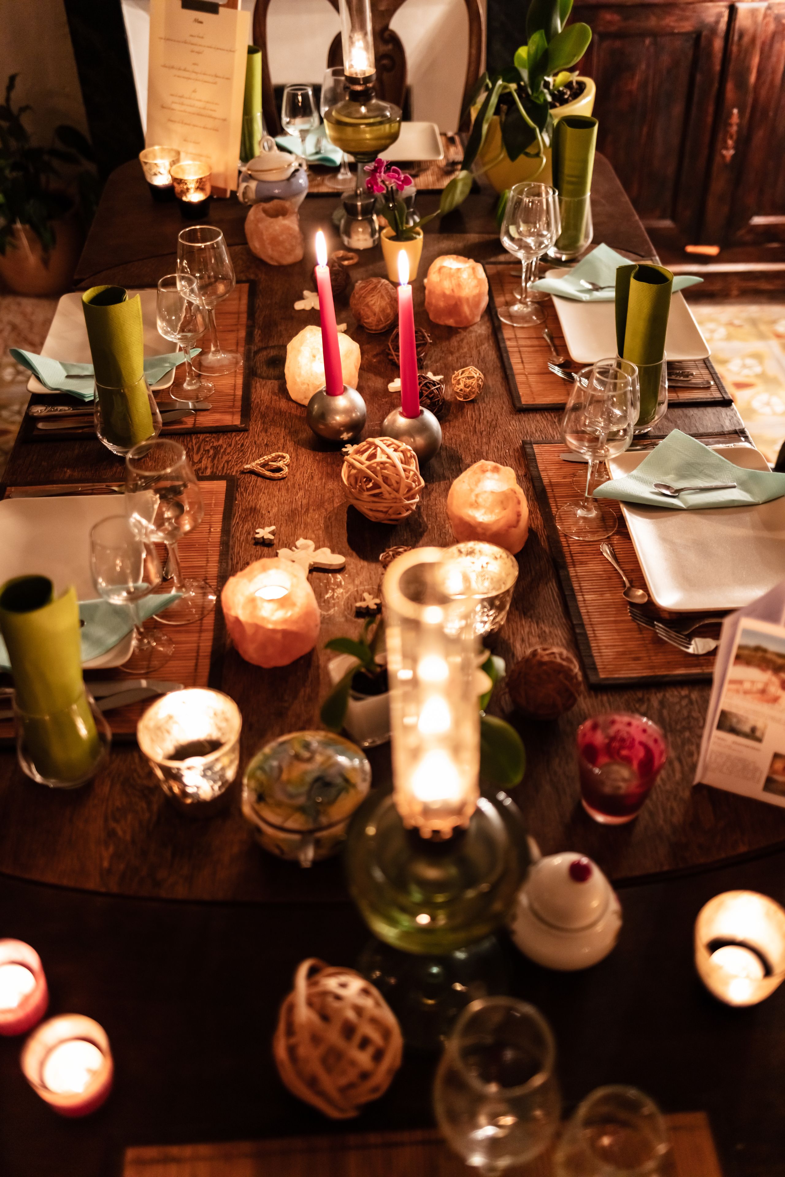 A dining table set with candles, glasses, and various decorative items.