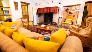 A cozy living room with a fireplace, yellow and beige sofas, and a wooden coffee table.