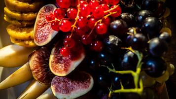 A fruit platter with sliced bananas, figs, red currants, and grapes.