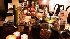 A table set for a meal with candles, glassware, and a menu.
