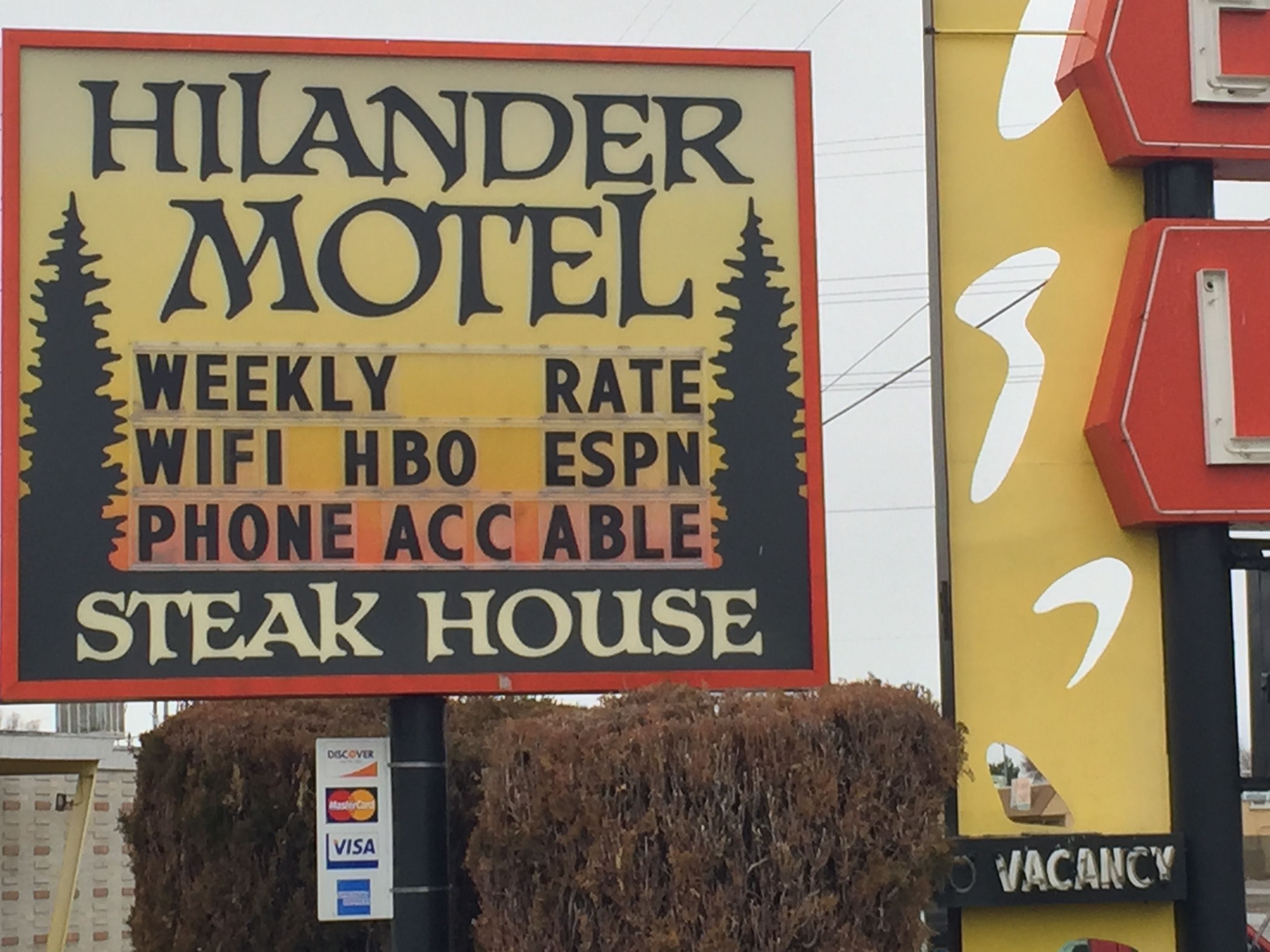 Letrero del motel Hilander que anuncia tarifas semanales, WiFi, HBO, ESPN, disponibilidad telefónica y restaurante de carne.
