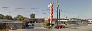 Un motel con un letrero llamativo, un estacionamiento y un edificio de techo plano.