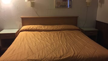 Een enkel bed met een houten hoofdbord, twee nachtkastjes en twee wandlampen.