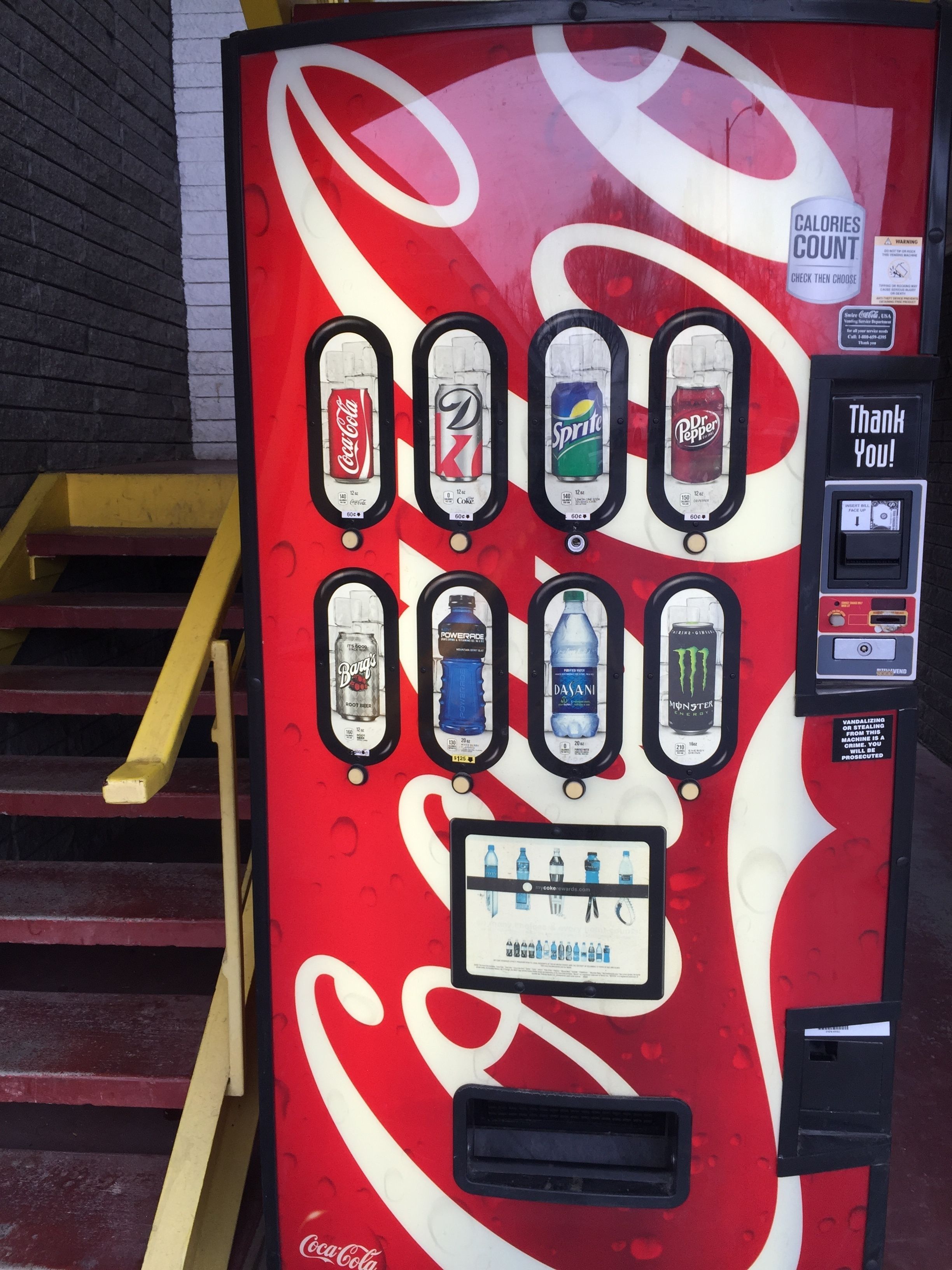 Un distributeur automatique de boissons de la marque Coca-Cola, proposant différents types de boissons et affichant le nombre de calories.
