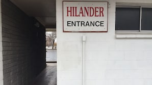 Un letrero que dice 'HILANDER ENTRANCE' sobre una pared blanca.