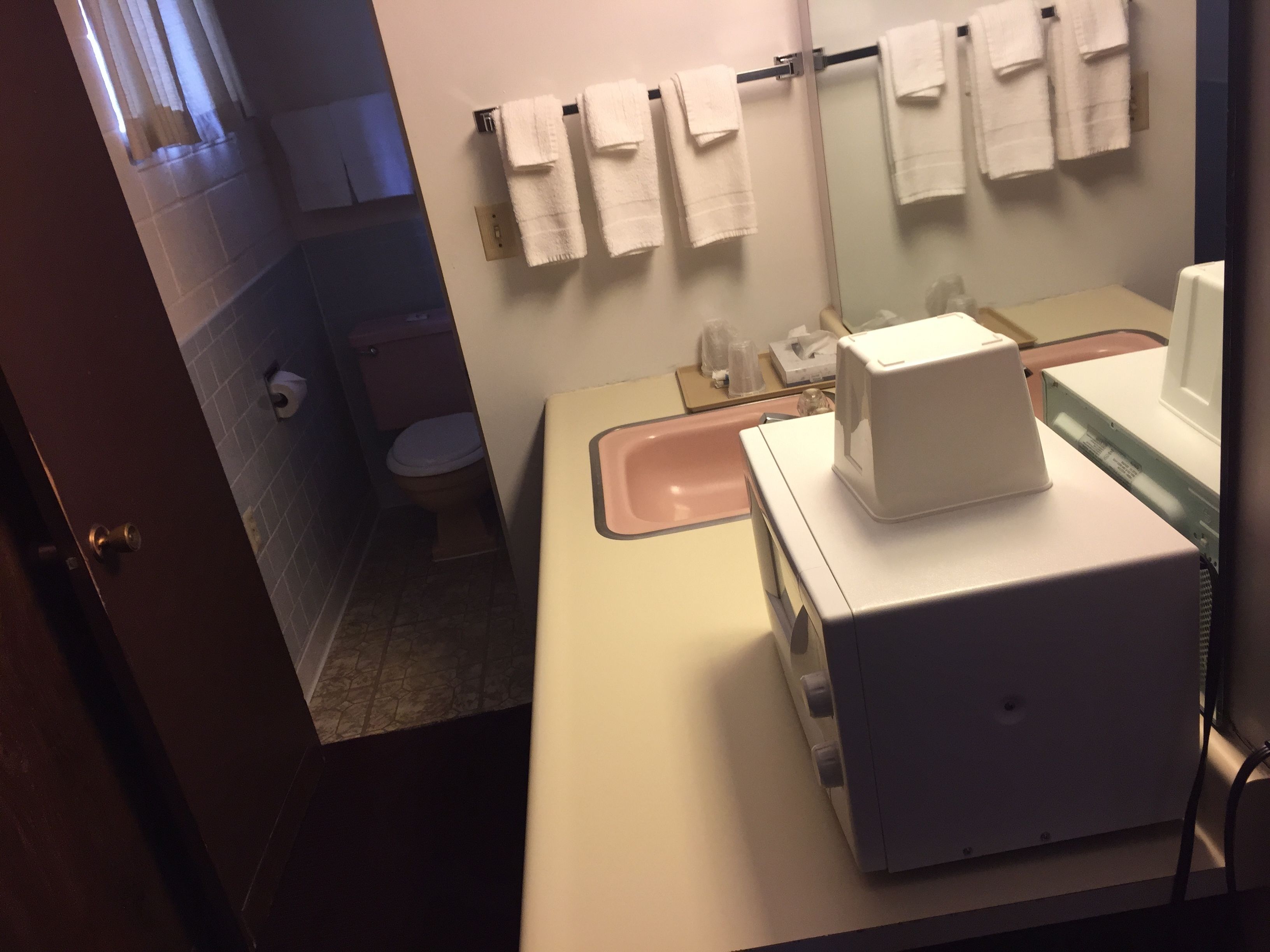 Une salle de bain équipée de toilettes, d’un lavabo et d’un miroir, avec des serviettes accrochées au mur.