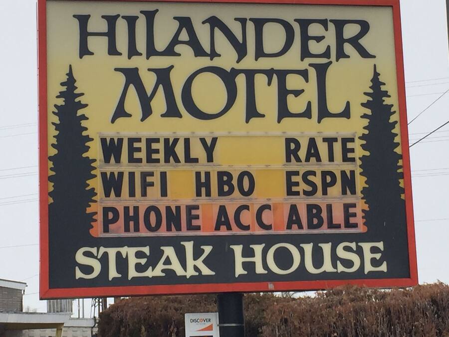 Señal del motel Hilander anunciando tarifas semanales, WiFi, HBO, ESPN, disponibilidad telefónica y un restaurante de carne.