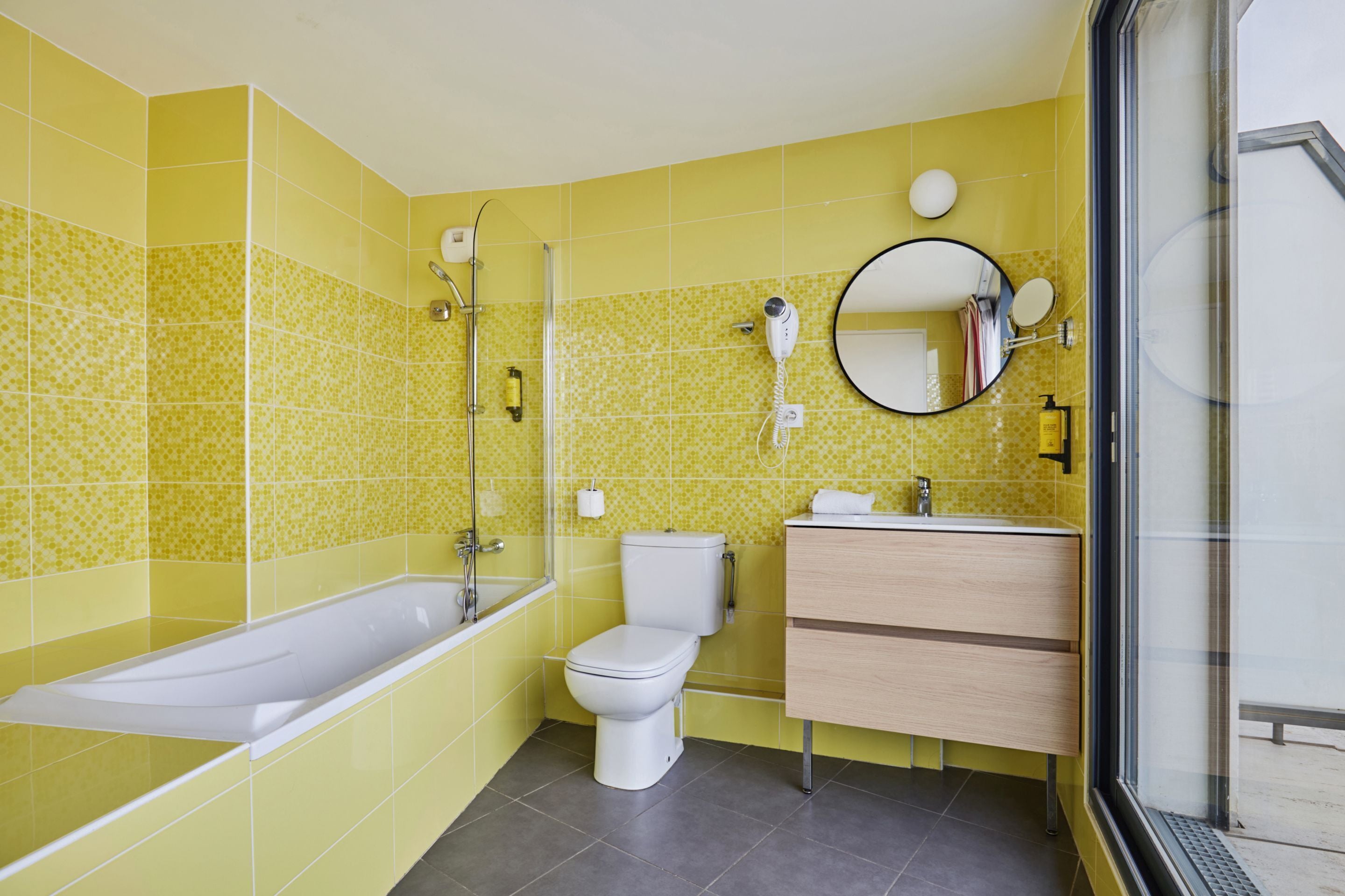 Un baño con bañera, inodoro y tocador con espejo.