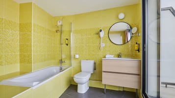 Un baño con bañera, inodoro y tocador con espejo.