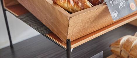 A wooden display case with pastries and bread.