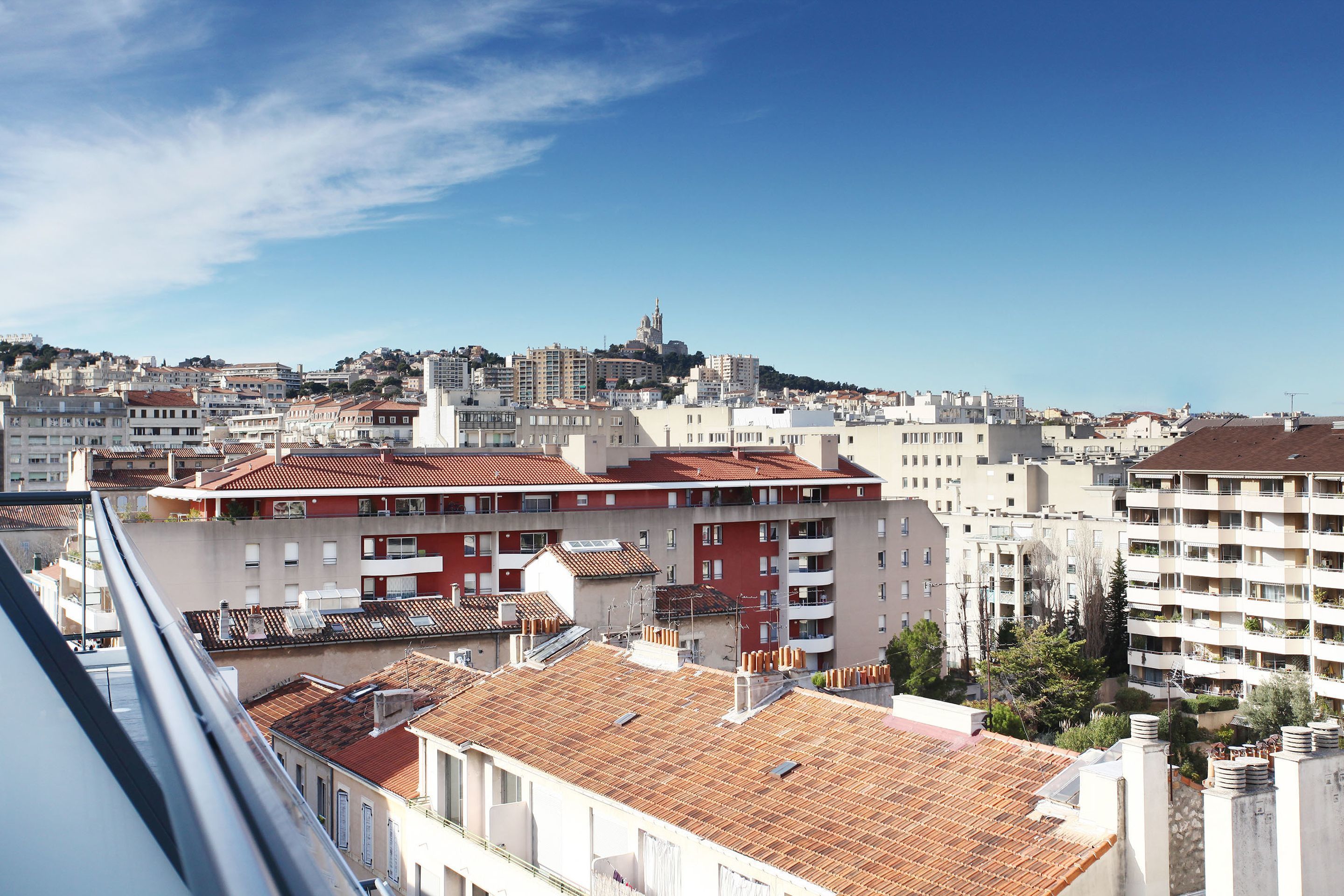 A cityscape with a prominent church on a hill, surrounded by residential buildings with red-tiled roofs.