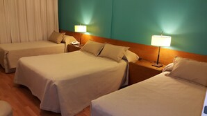 A hotel room with three single beds, each with a bedside table and lamp. - Hotel Avenida (Buenos Aires)
